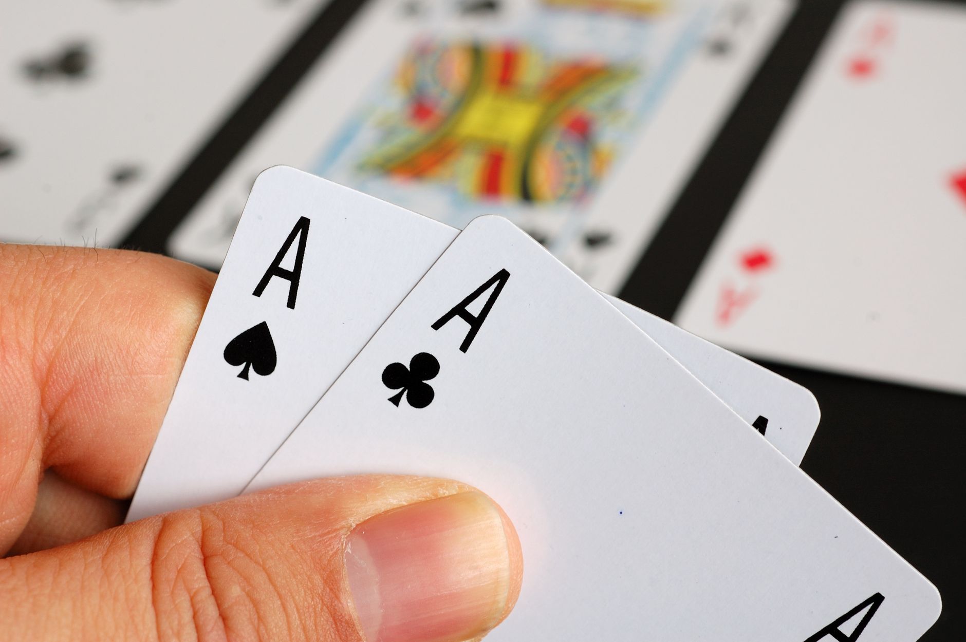 Detailed close-up of a hand holding aces in a poker game, symbolizing luck and strategy.