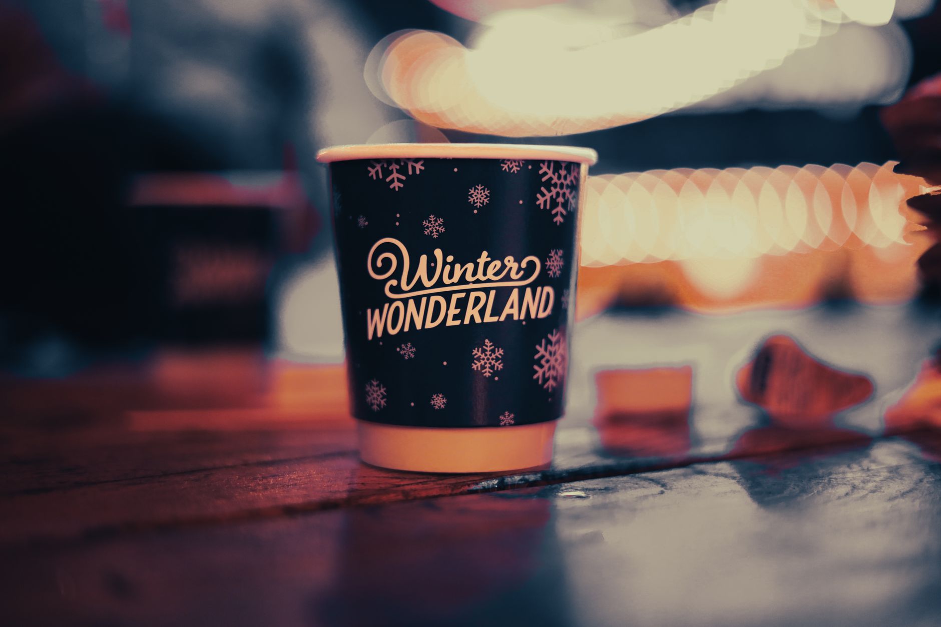 A cozy disposable cup with 'Winter Wonderland' text and snowflakes on a wooden table creates a festive feel.