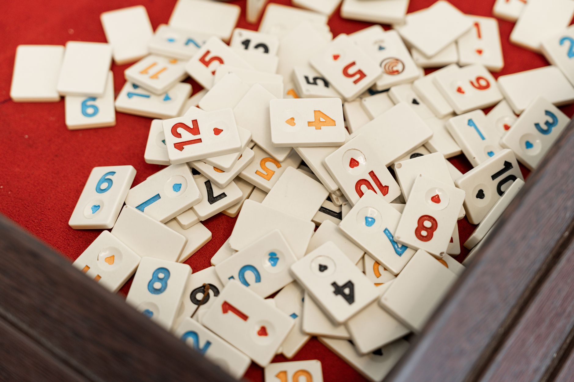 A collection of numbered game tiles scattered on a red surface, perfect for game night themes.
