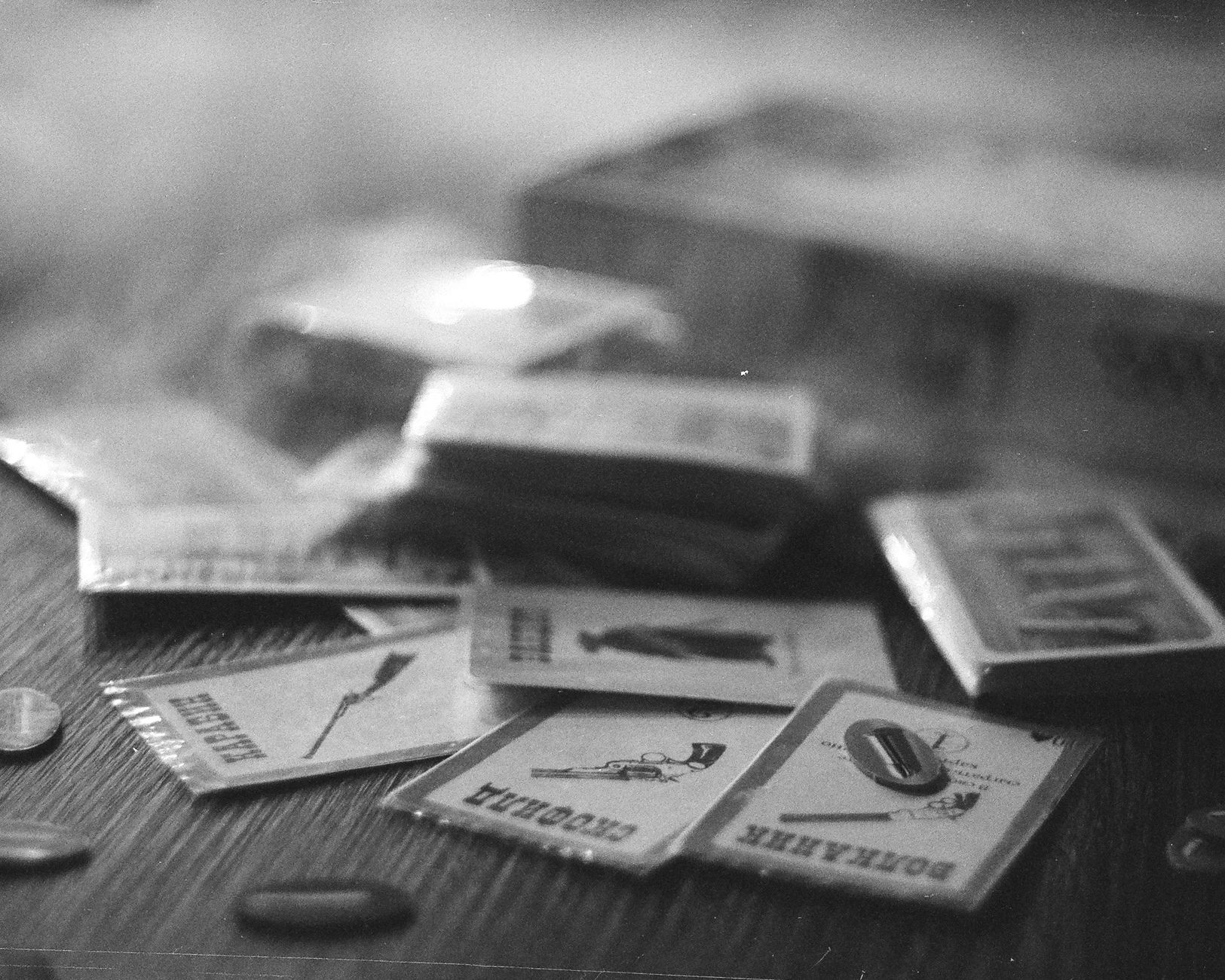 Black and white close-up of vintage board game cards scattered on a wooden table.