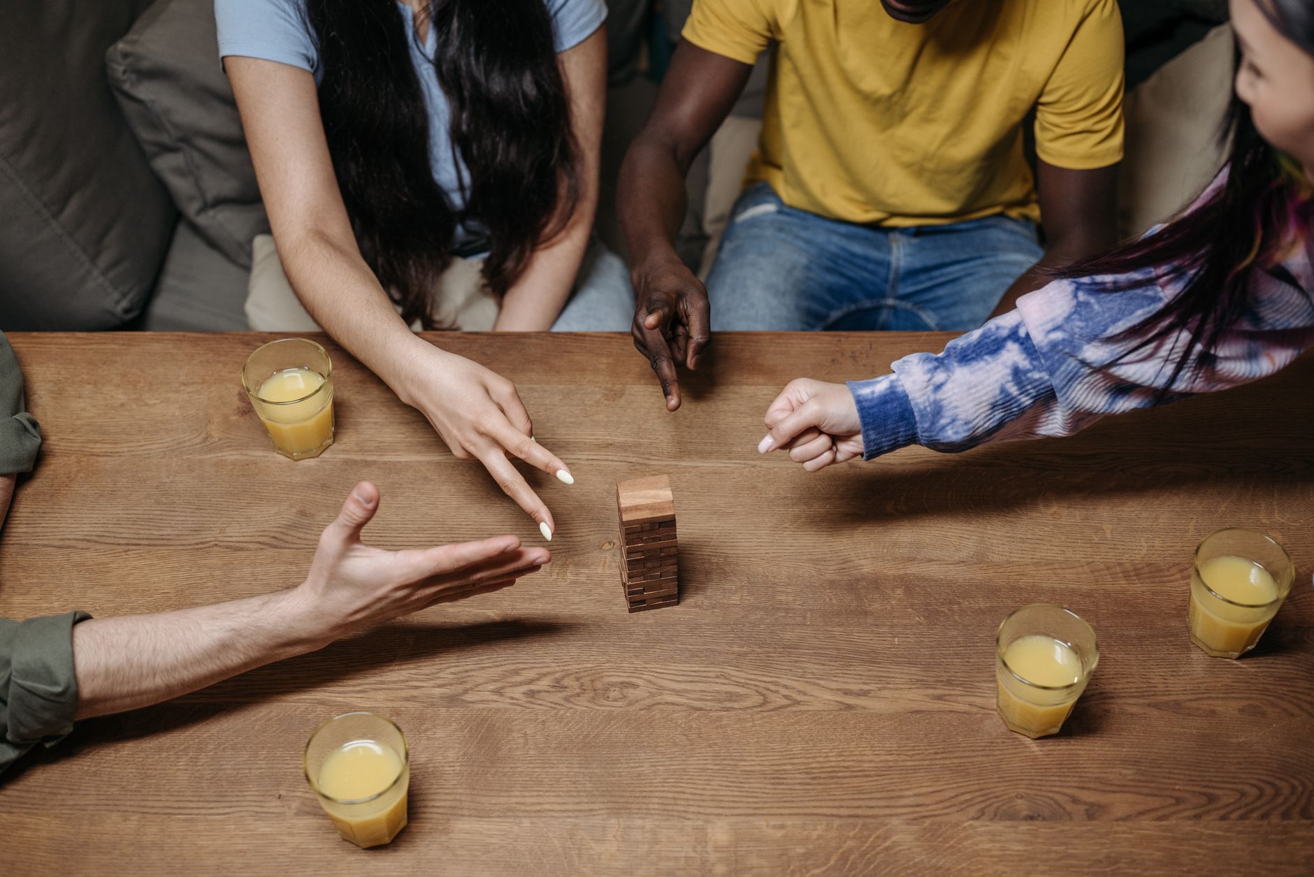 A group of diverse friends playing a tabletop game with drinks, showcasing social interaction and fun.