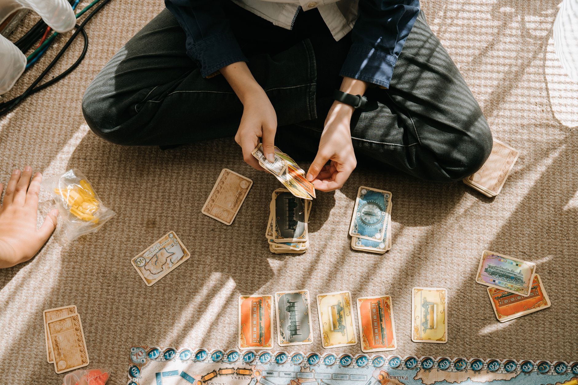 A child engages in a fun board game indoors, surrounded by cards and game pieces.