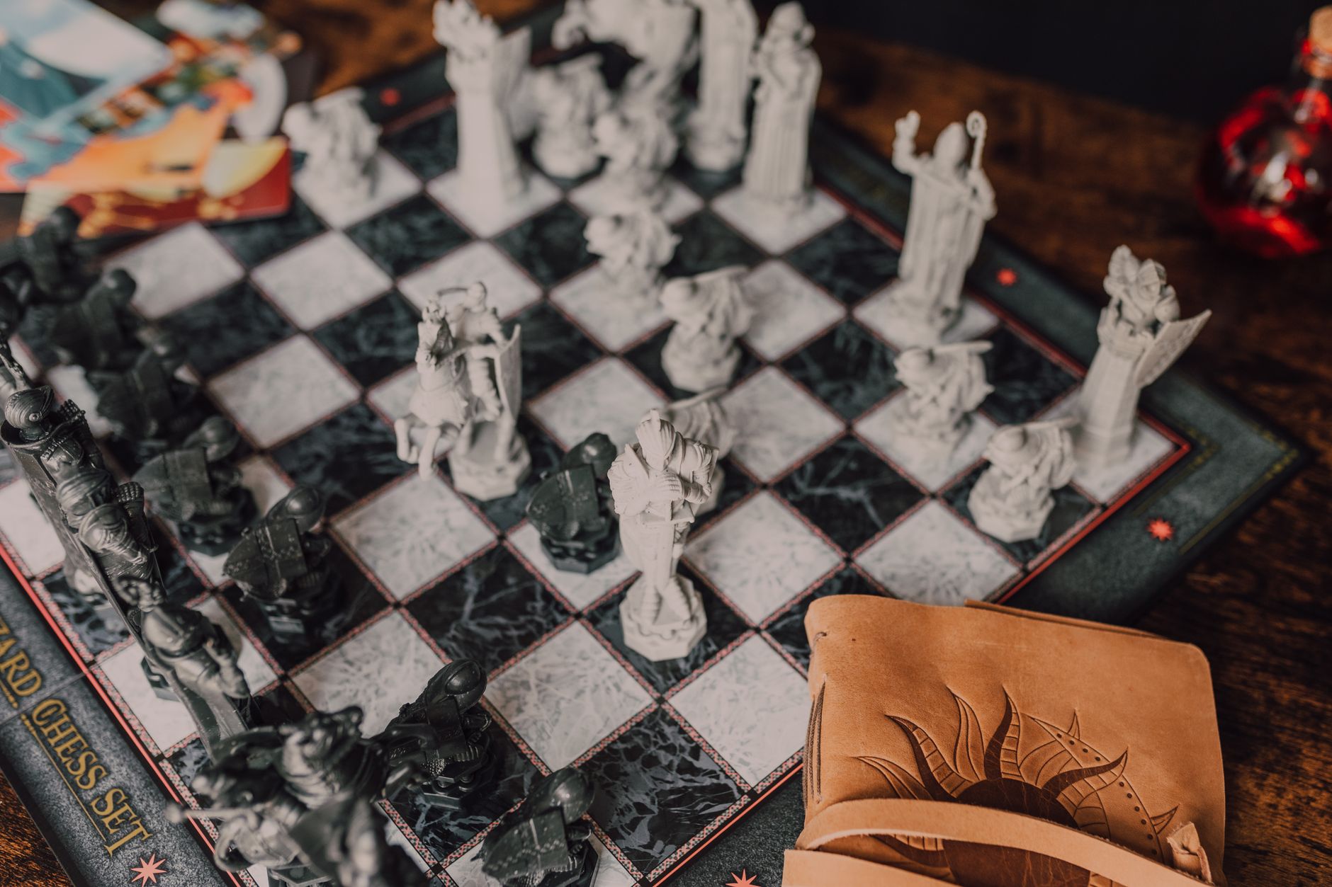 Close-up of a detailed wizard-themed chess set on a wooden table with game card.