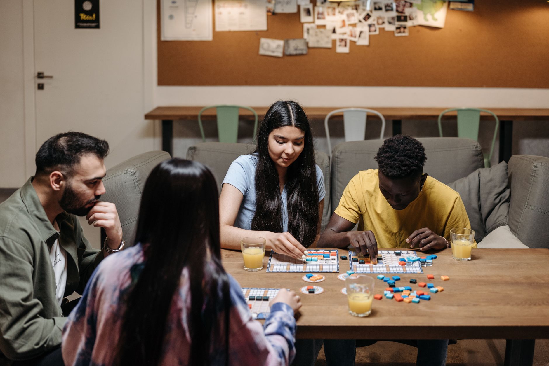 A group of friends enjoying a board game with drinks at a cozy table setting.