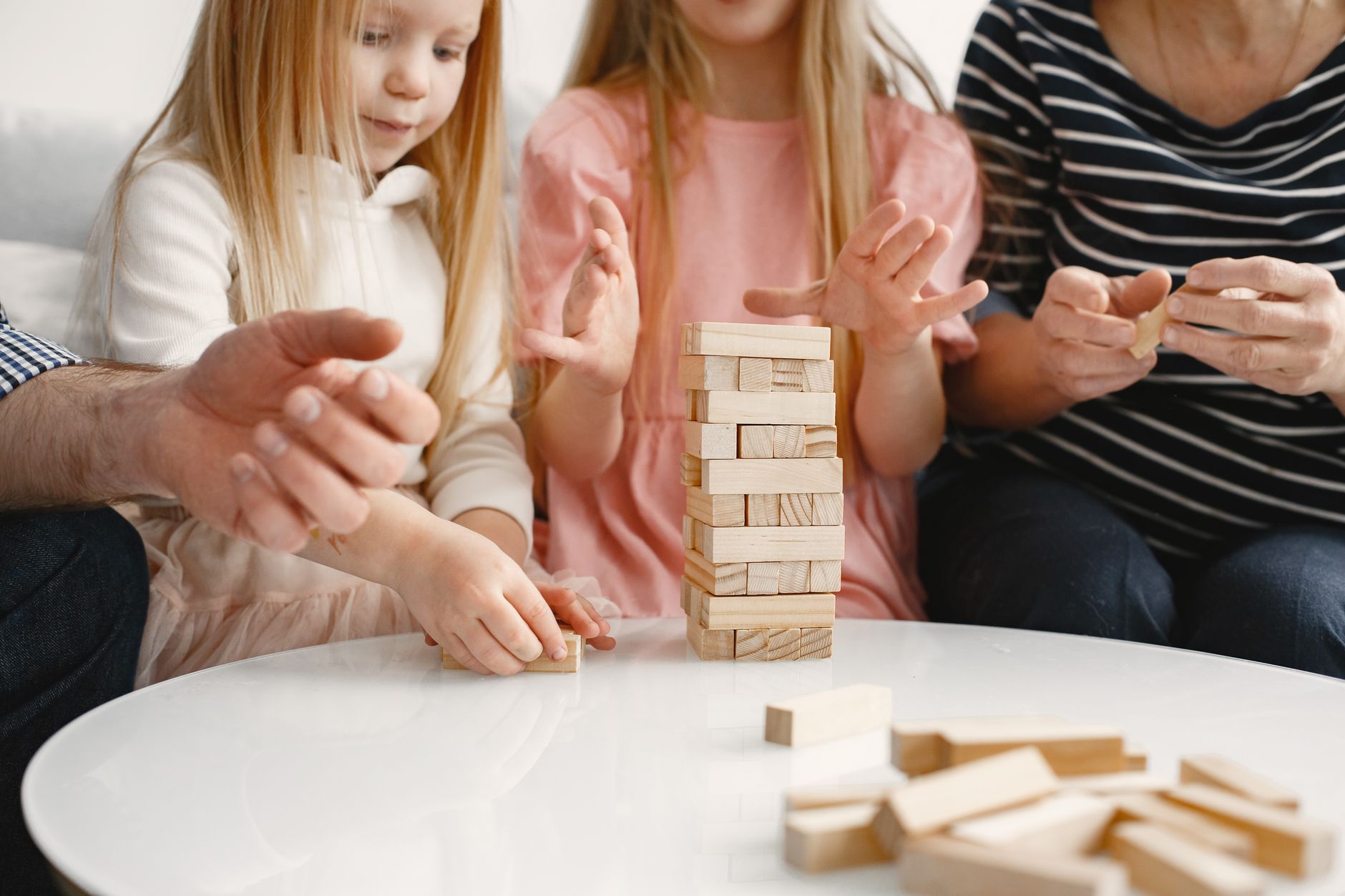 A family playing Jenga indoors creates a bonding experience and fun moment together.