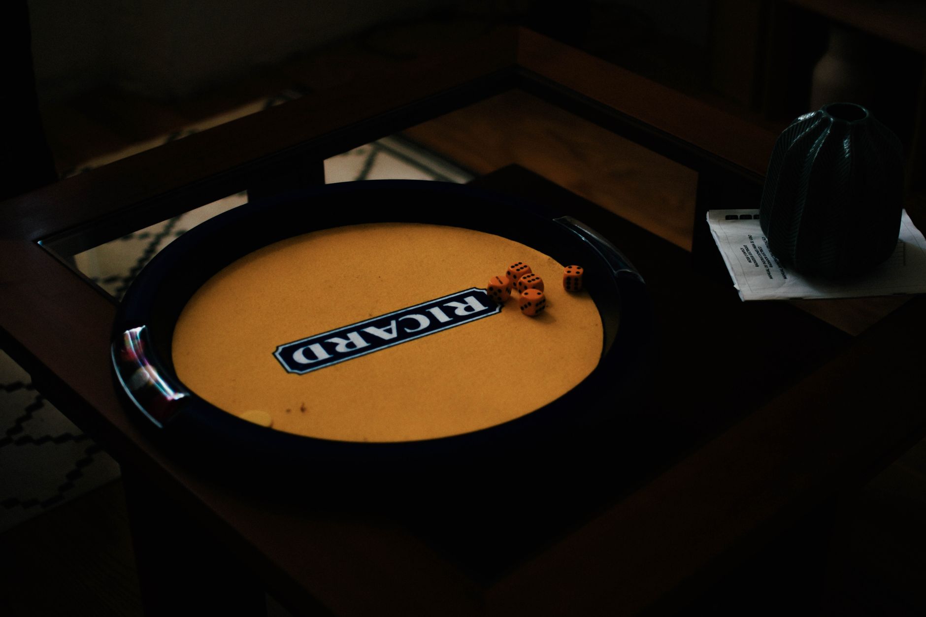 Close-up of a dice game setup on a wooden table with soft lighting creating a moody atmosphere.