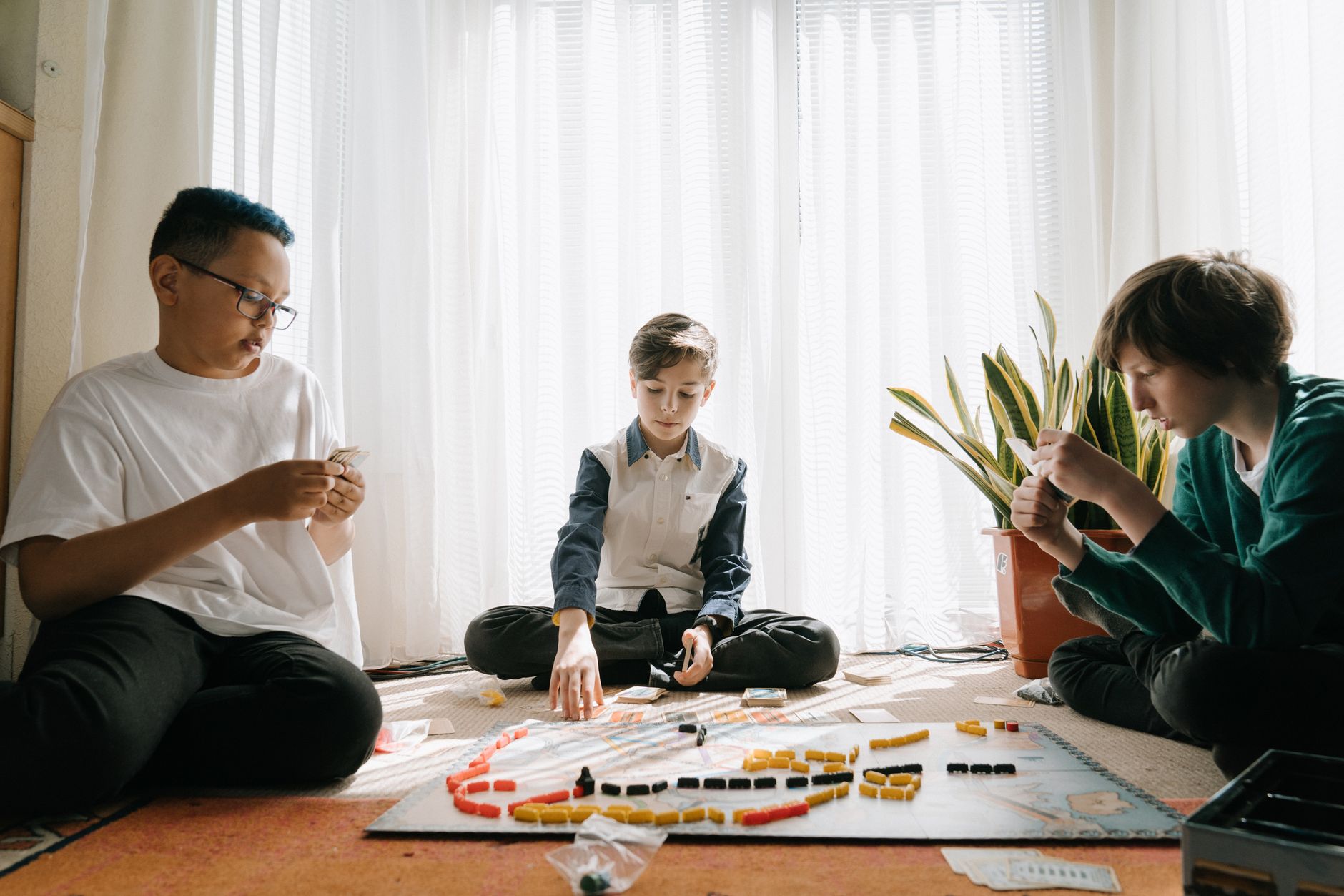 Three children deeply focused while playing a board game together indoors.