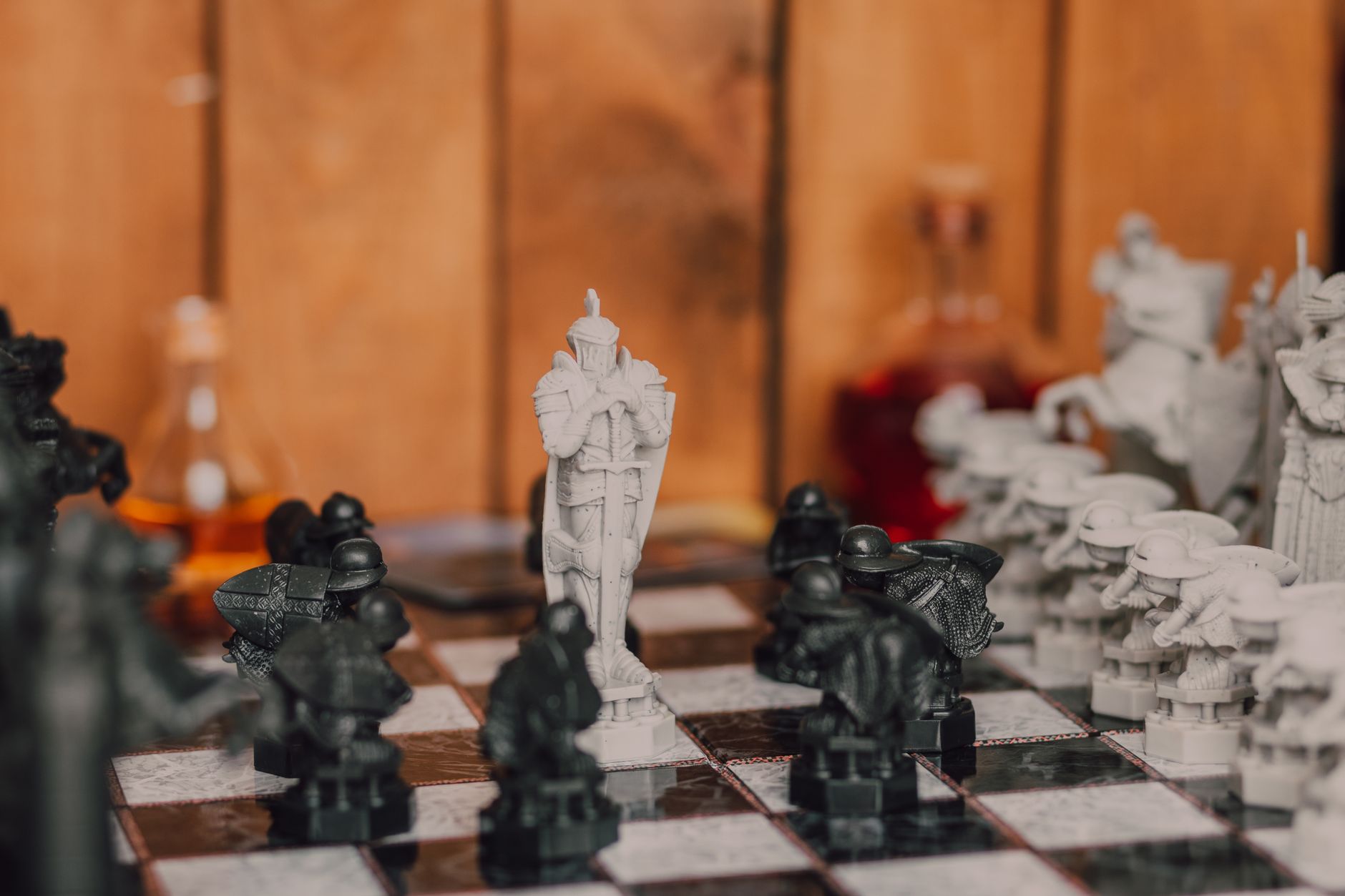 Close-up of a fantasy-themed chess set with intricate black and white pieces in a warm indoor setting.