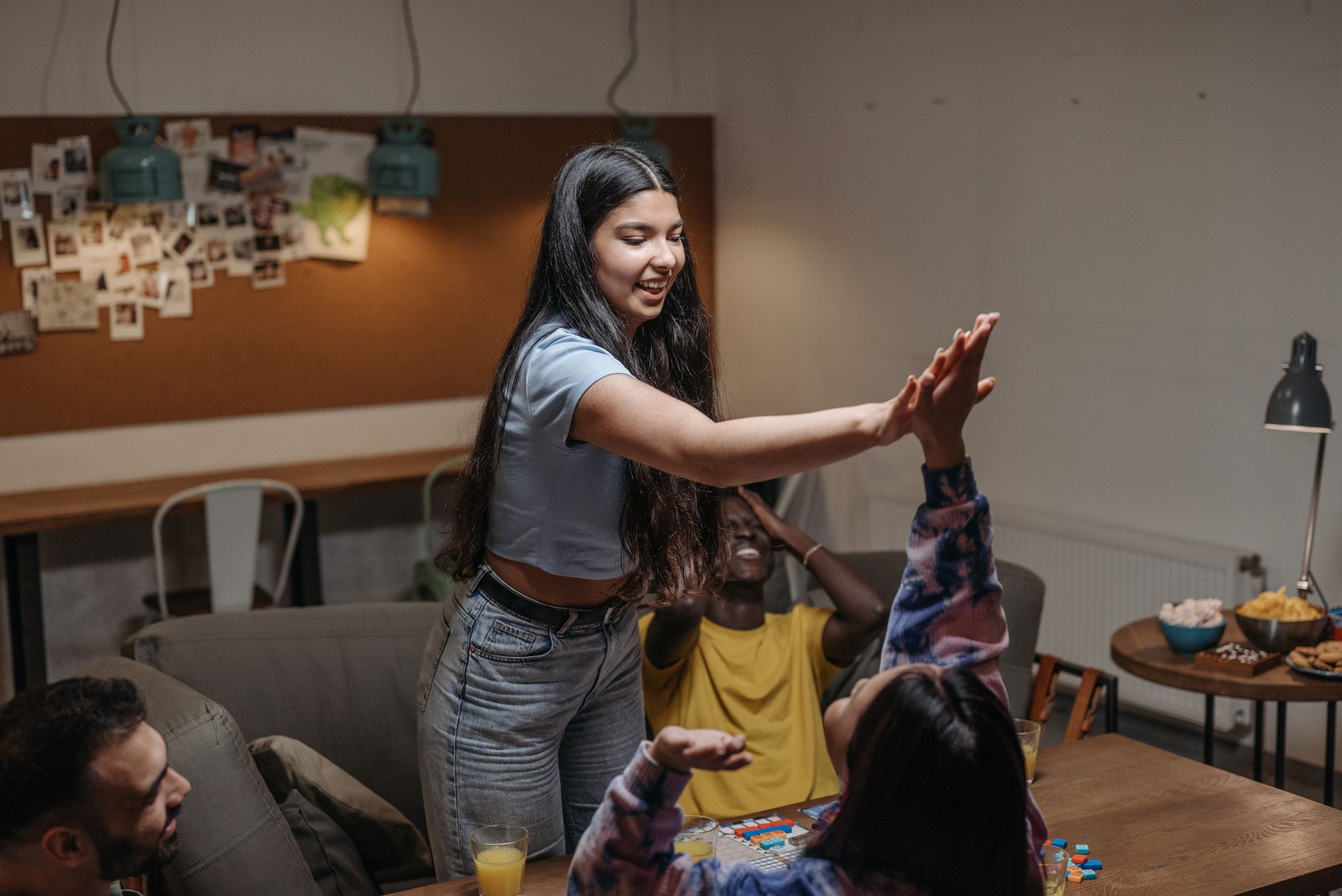 Group of friends having fun during a game night at home, sharing laughter and high fives.