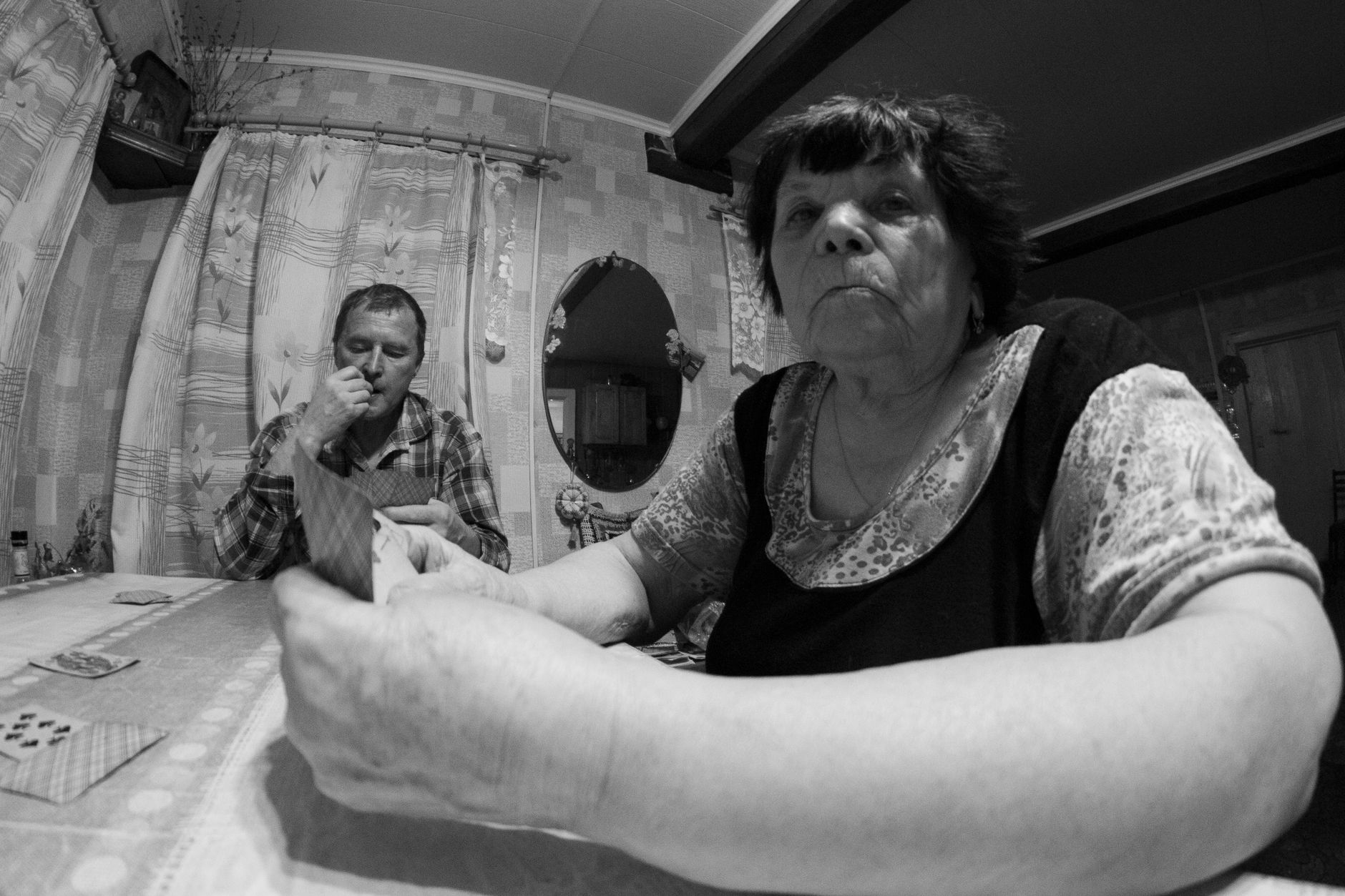 A senior man and woman playing cards at a table in their home, capturing a moment of leisure.