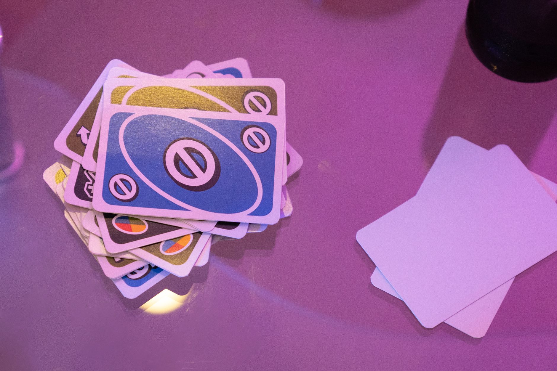 Stack of colorful Uno cards on a pink surface, vibrant and playful game setup.