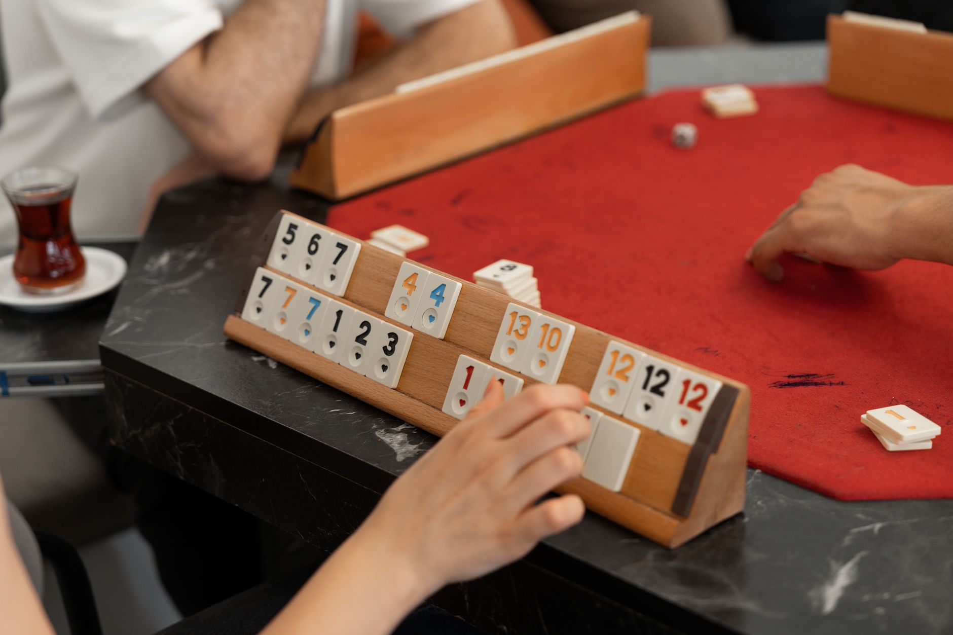 A relaxed scene of friends playing Rummikub indoors around a table in Türkiye.