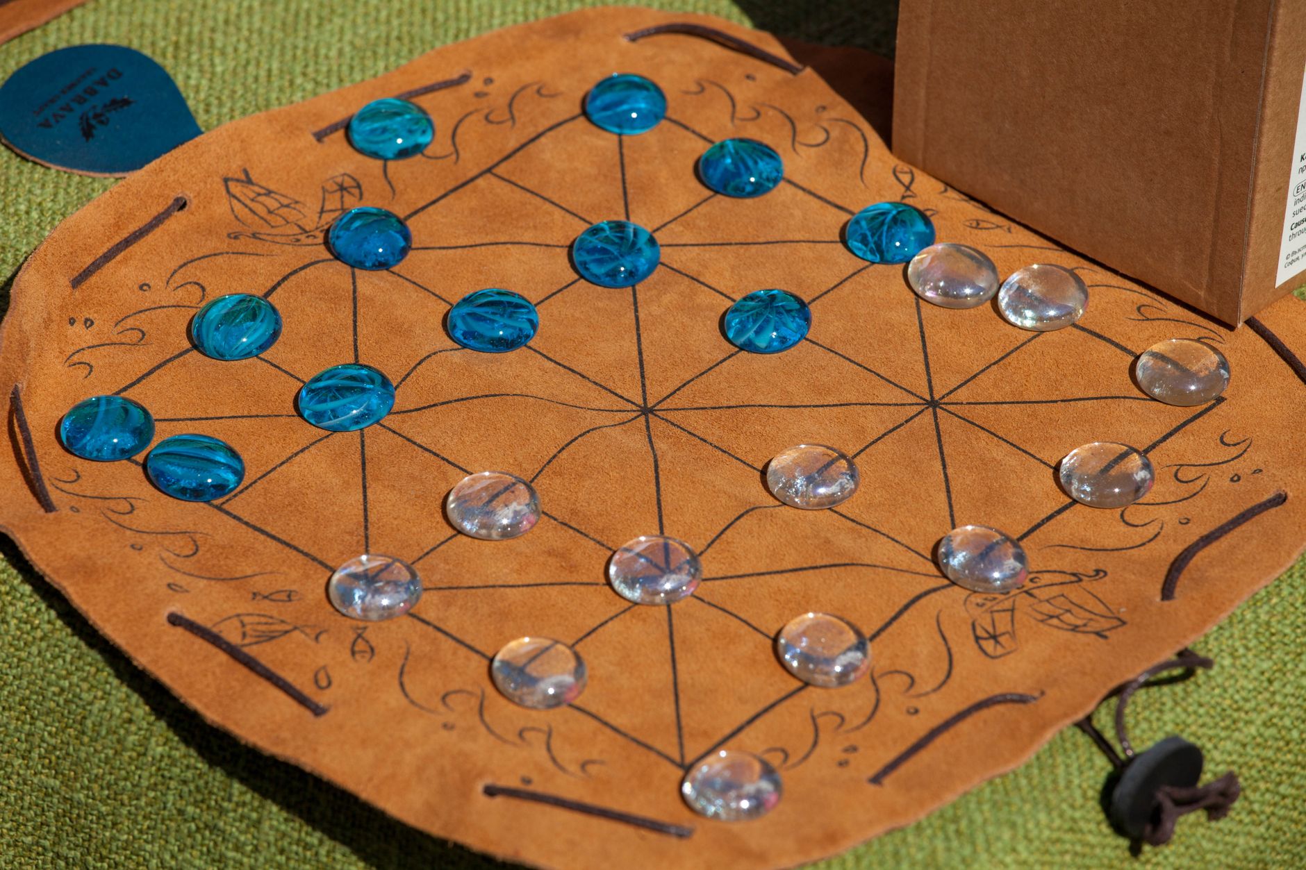 Colorful glass pieces on a leather board game mat, offering a historical or strategy theme.