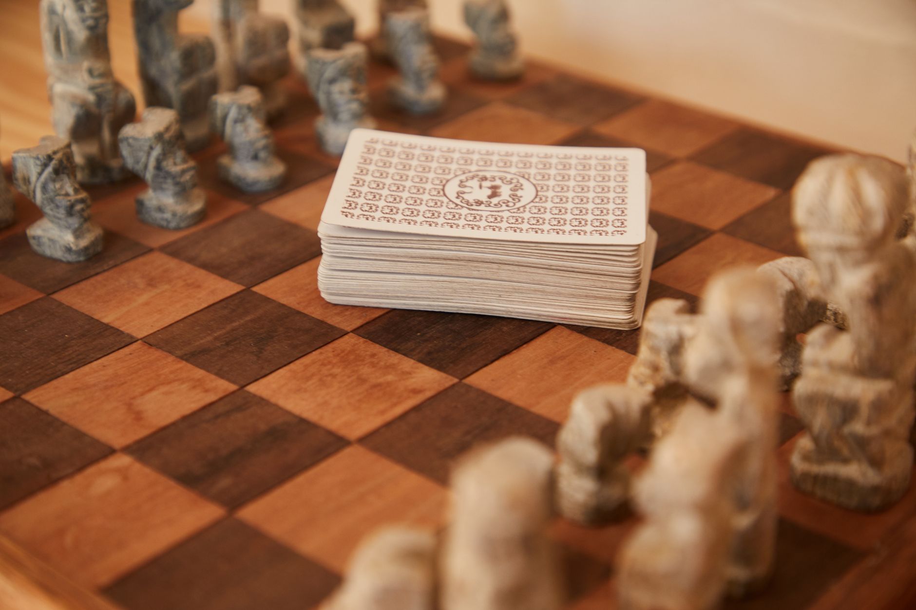From above of brown chessboard with vintage chess pieces and stack of cards