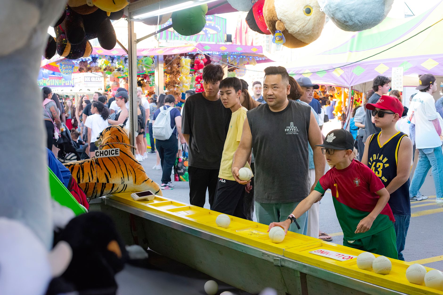 A diverse group of people engages in a fun carnival game, surrounded by vibrant festival activities.
