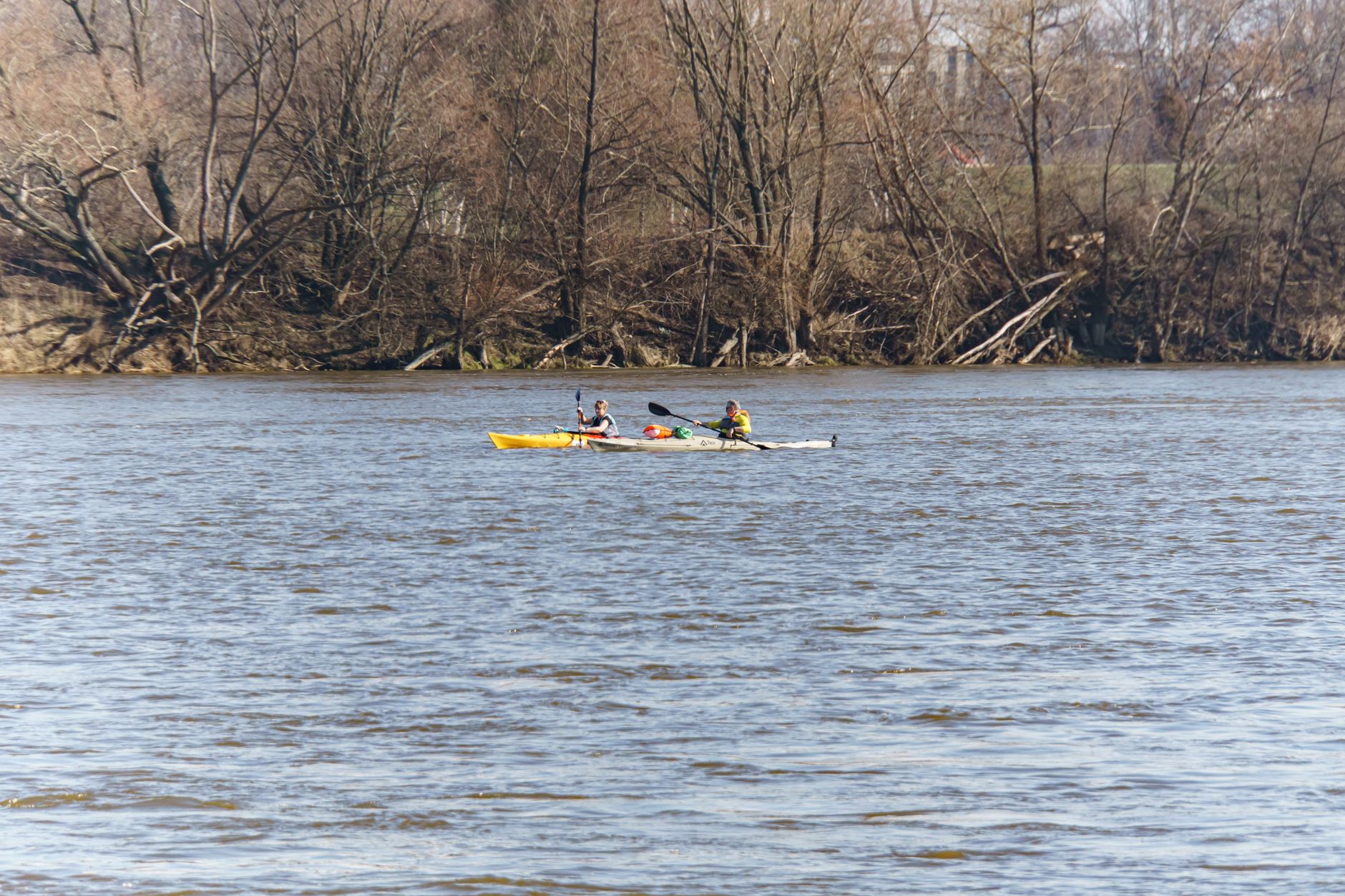 Three kayakers enjoy a peaceful ride on a Warsaw lake surrounded by autumn trees.