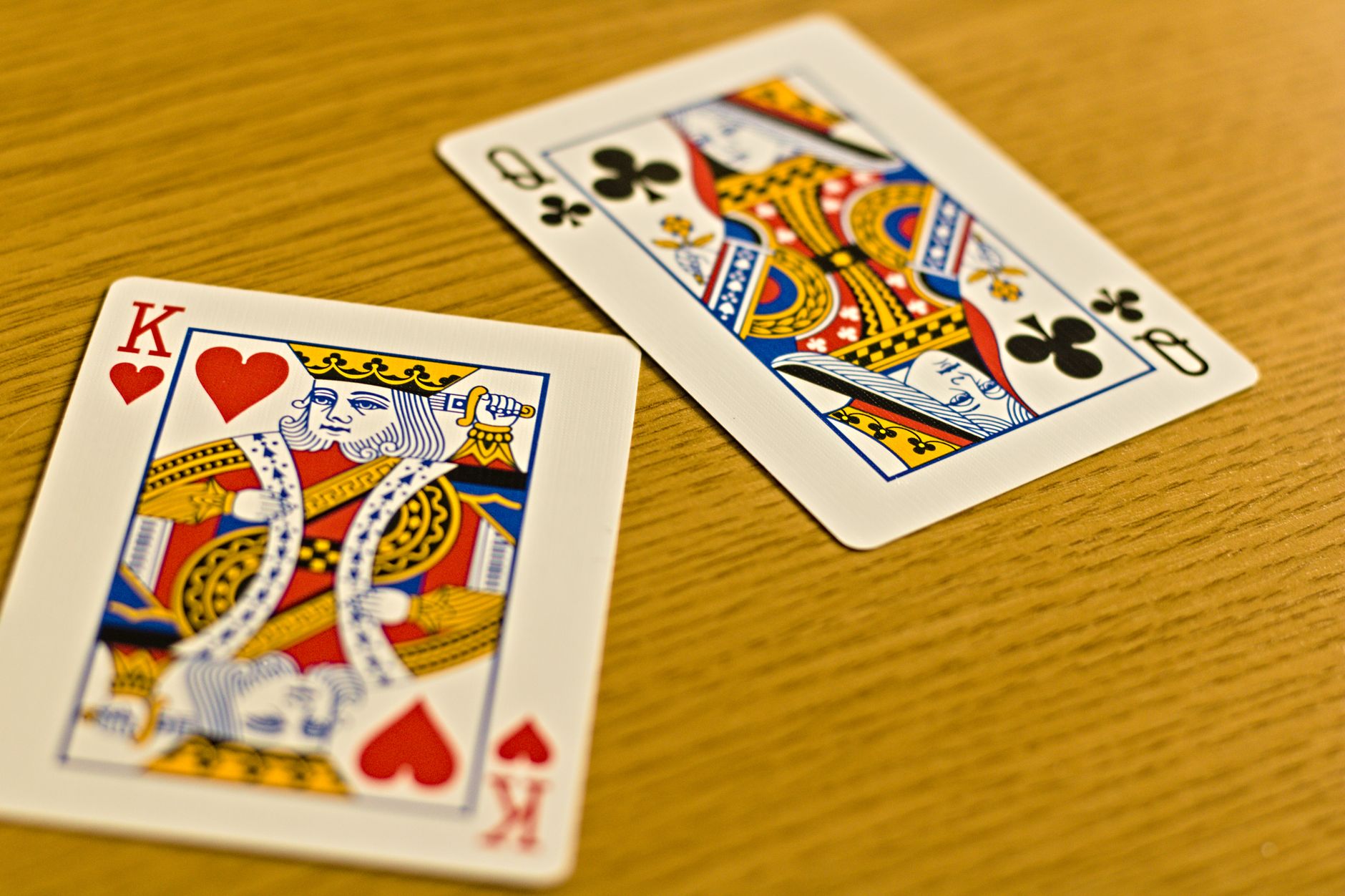 Close-up of king and queen playing cards on a wooden table with a bright and vivid design.