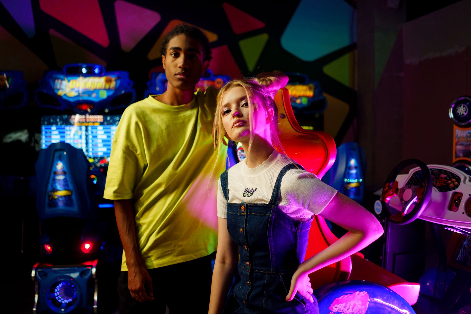 Two young adults enjoying a night at a colorful arcade center, surrounded by vibrant neon lights and arcade machines.