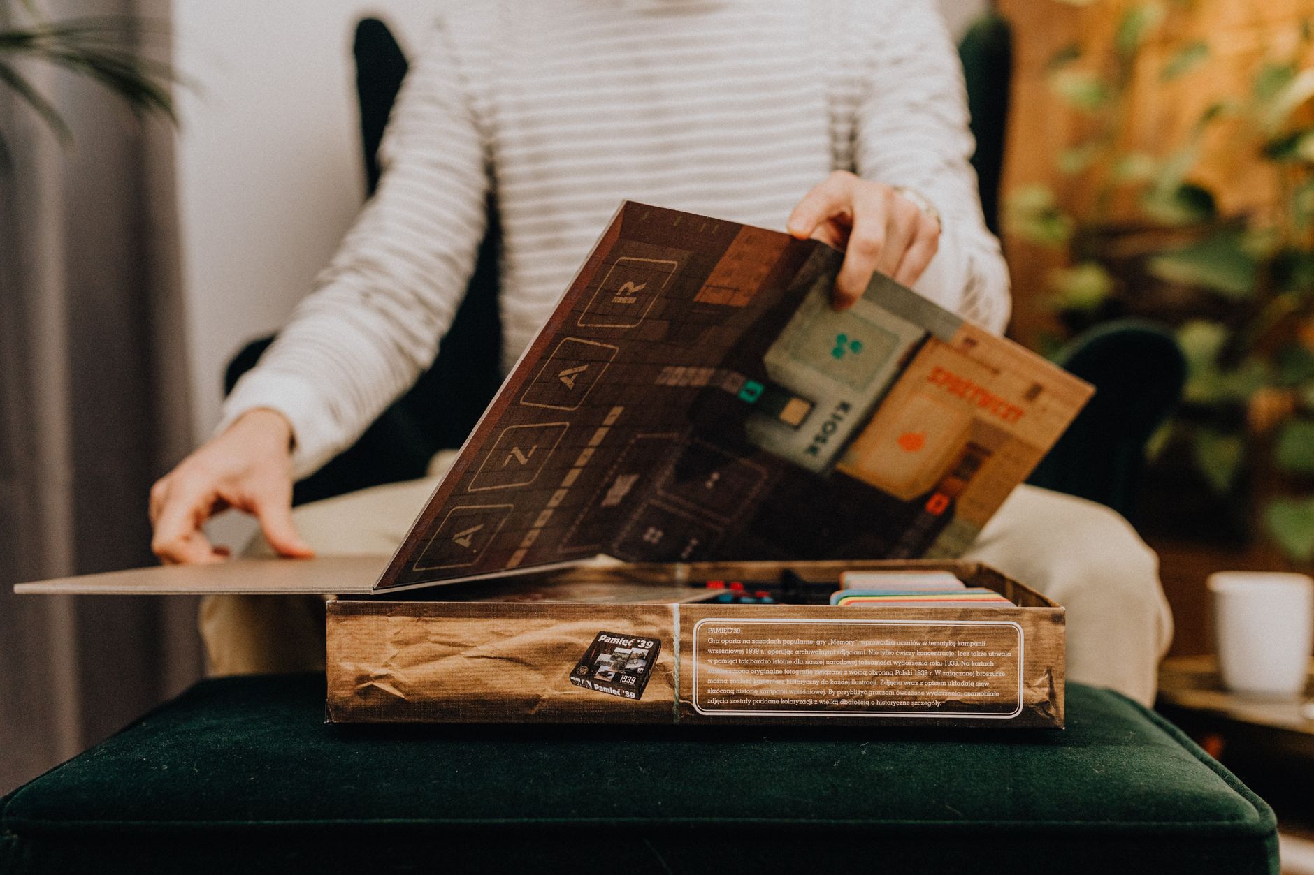 A person is seen unpacking a board game, showcasing leisure and relaxation at home.