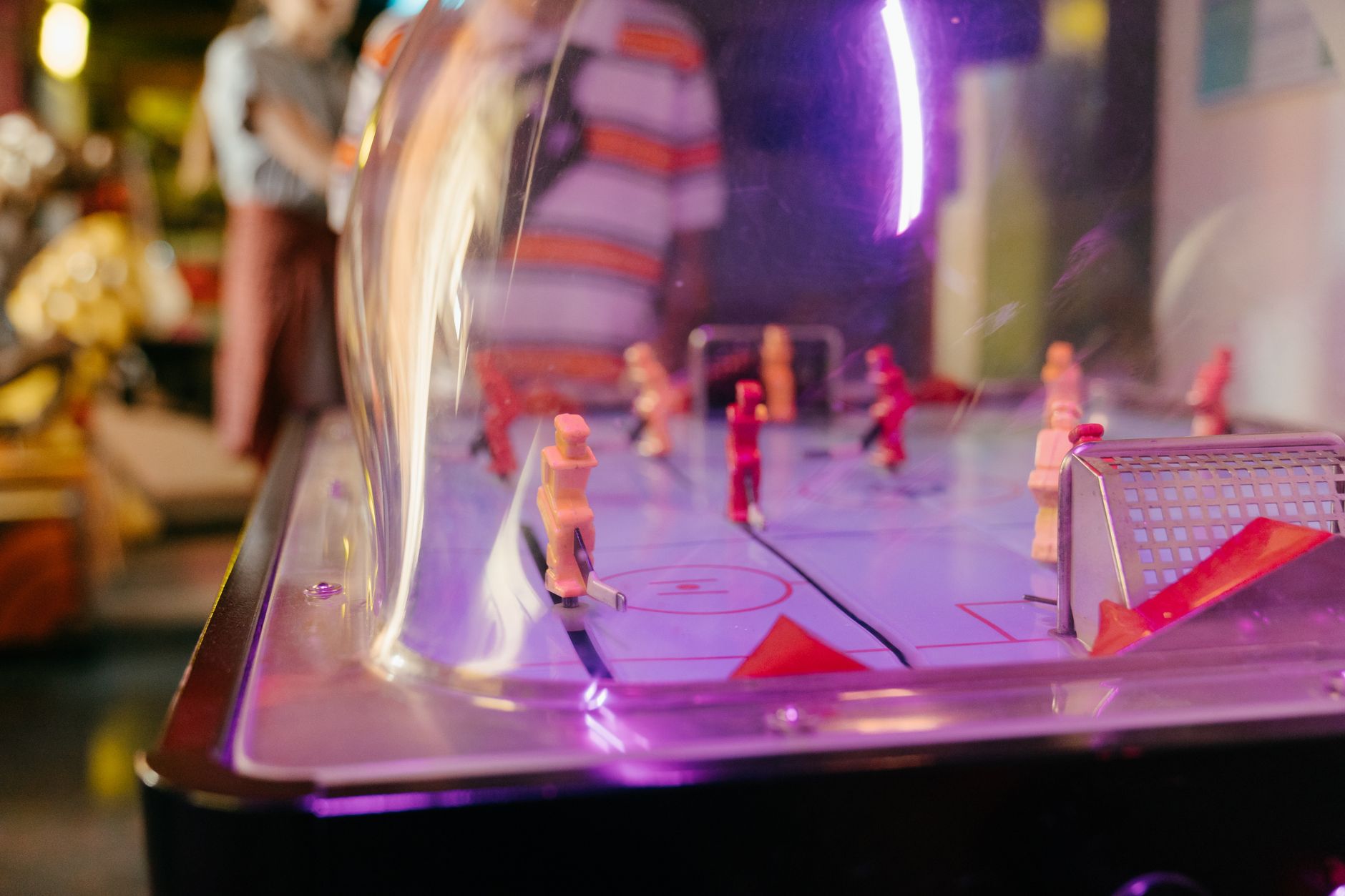 A lively game of dome hockey under vibrant lights indoors, capturing playful moments.
