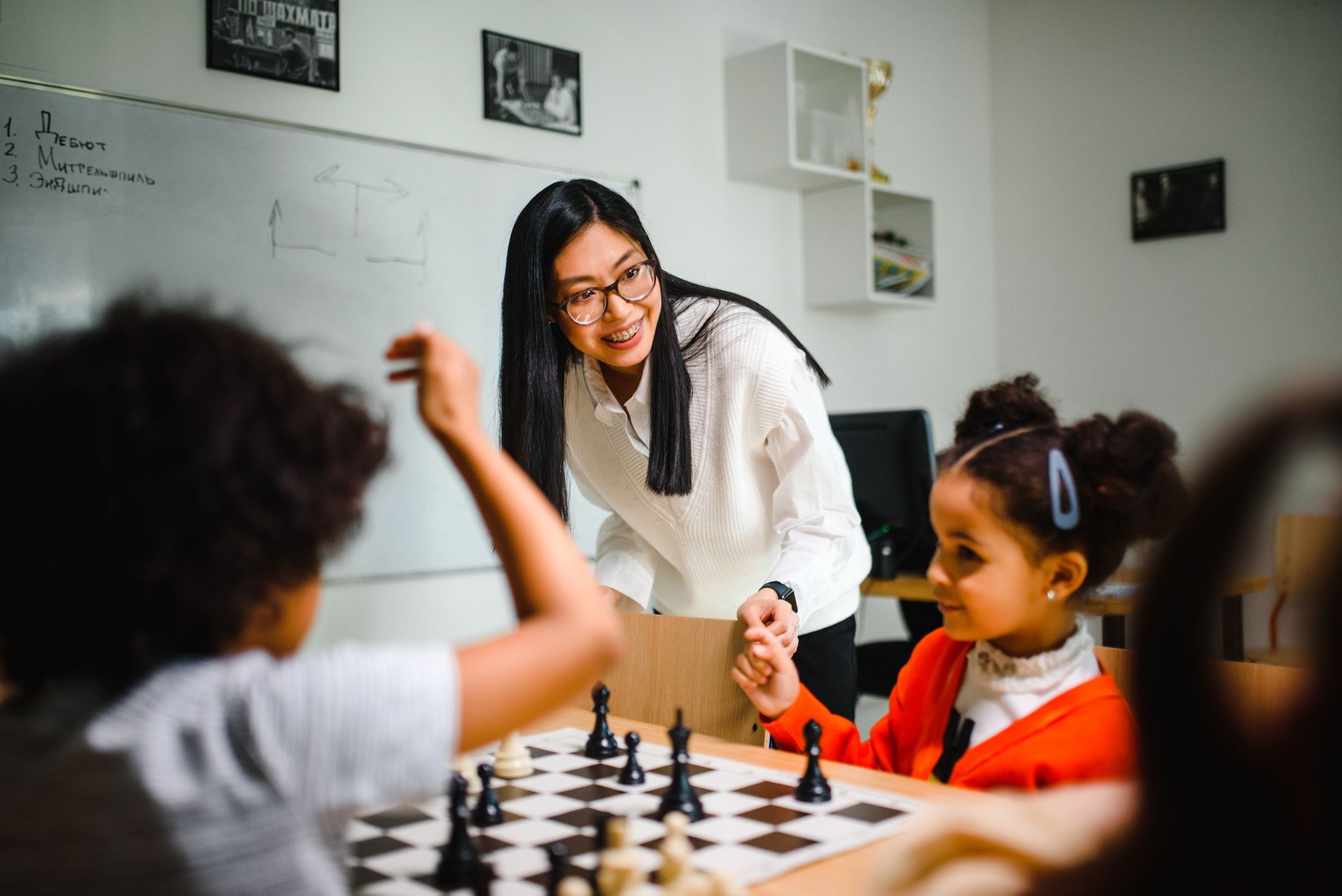 Engaging classroom scene with teacher guiding children in a chess game, fostering learning and fun.