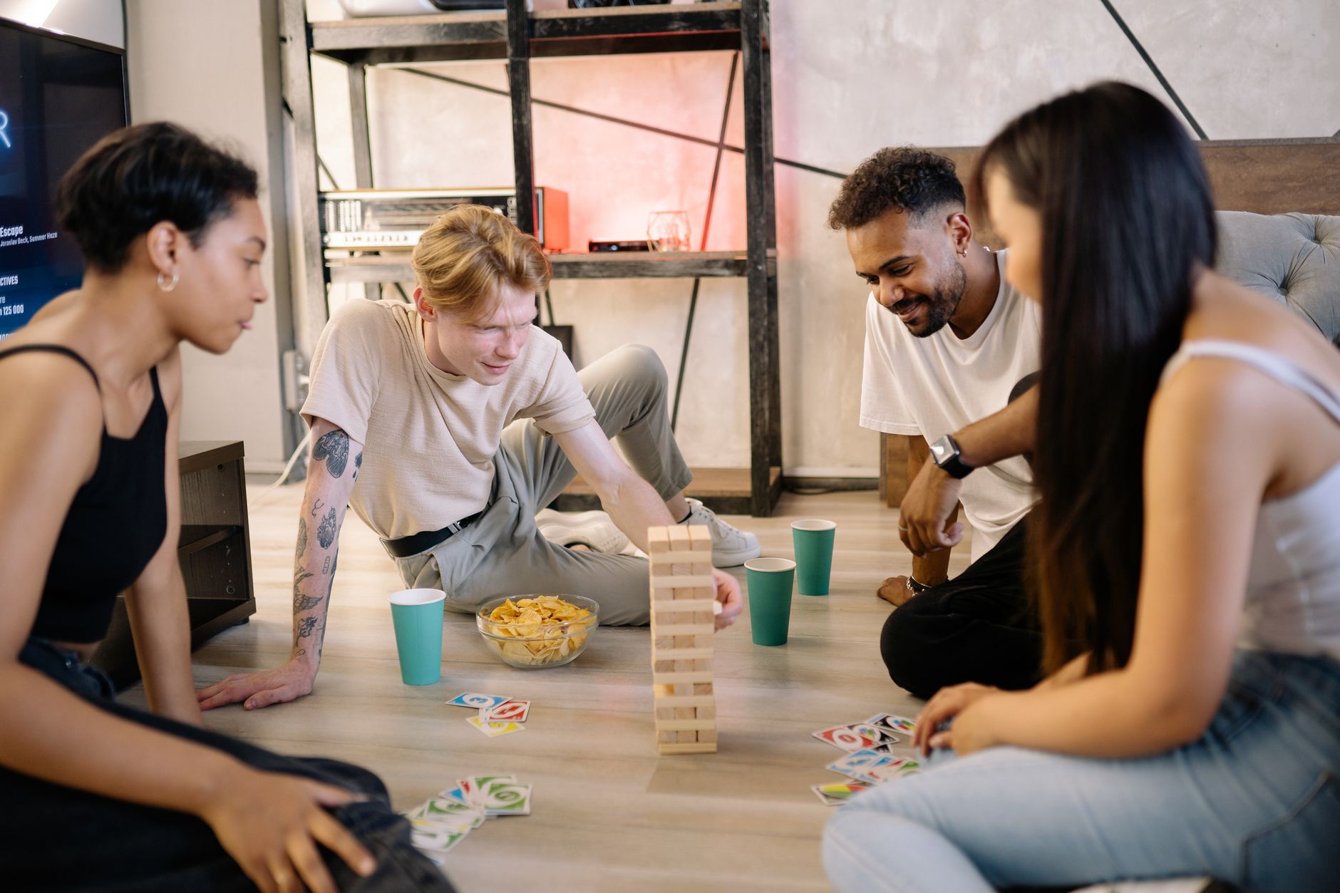 A diverse group of friends playing board games and cards indoors for entertainment.
