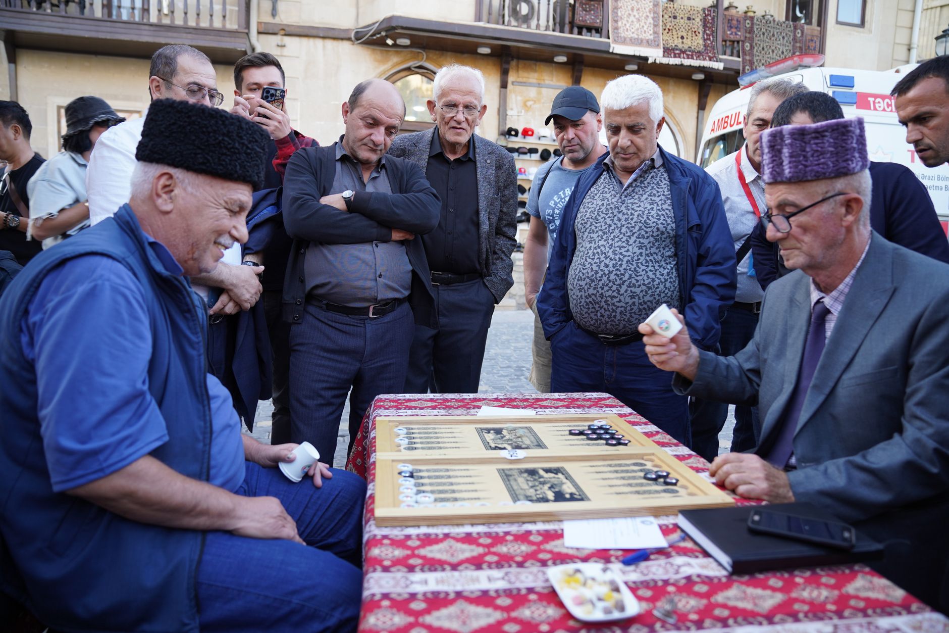 A group of men engaged in an intense game of backgammon outdoors.