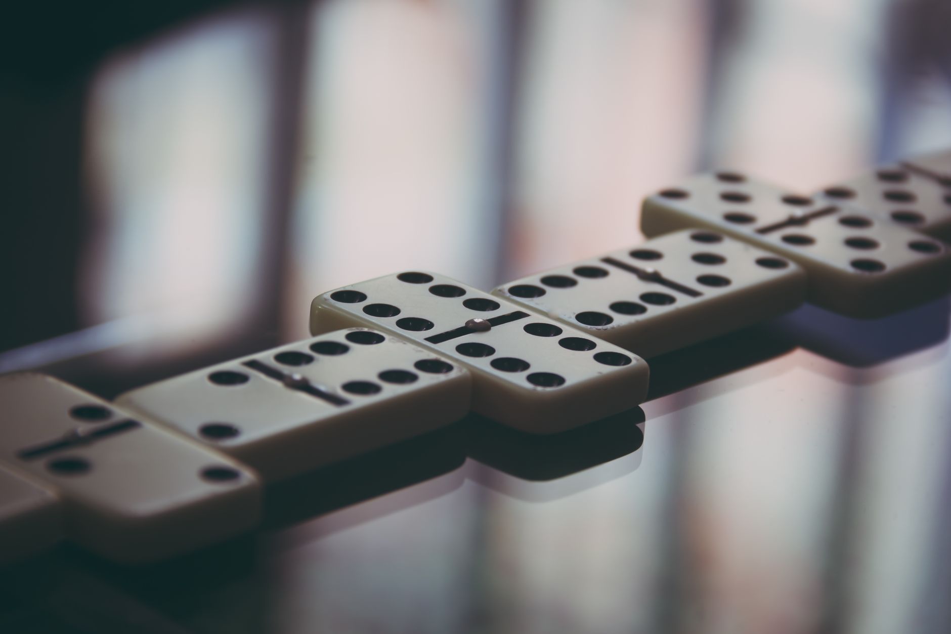 Artistic close-up of domino pieces on glass, highlighting the strategic game setup.