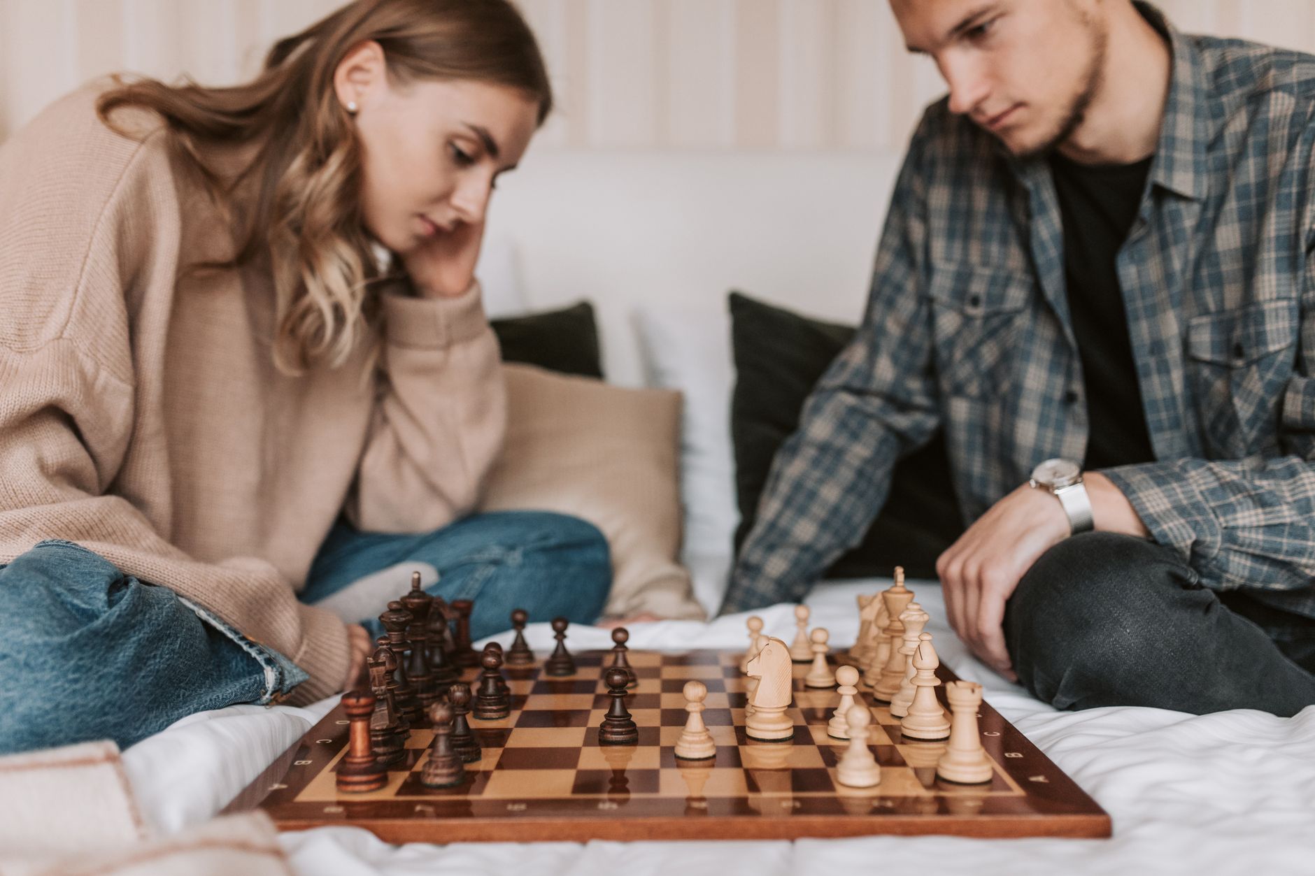 A young couple deeply focused on a chess game in a cozy indoor setting.